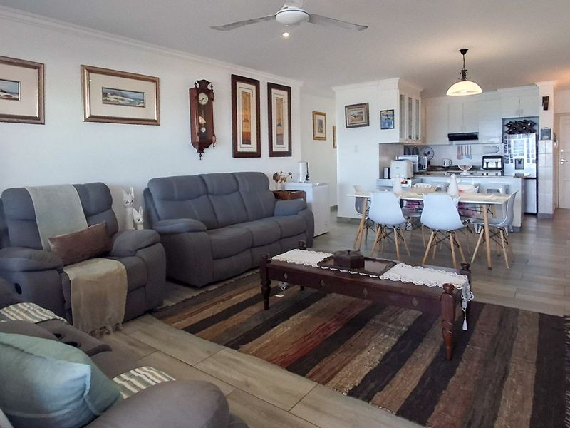 Spacious open-plan living and dining area featuring tiled flooring, a ceiling fan, and a functional kitchen with built-in appliances.