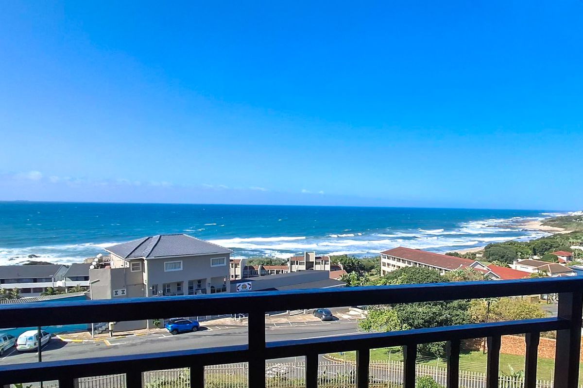 Elevated coastal view overlooking the ocean, surrounding residential buildings, and street infrastructure from a balcony.