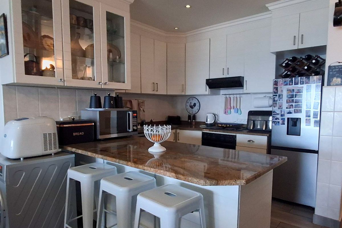 A functional kitchen featuring granite countertops, ample built-in cabinetry, a tiled backsplash, and integrated appliances including an oven and extractor fan.