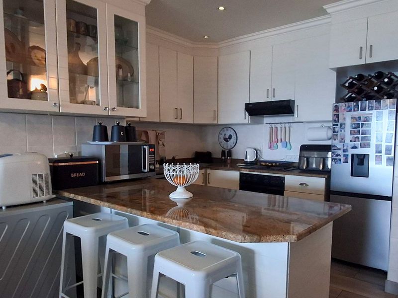 A functional kitchen featuring granite countertops, ample built-in cabinetry, a tiled backsplash, and integrated appliances including an oven and extractor fan.