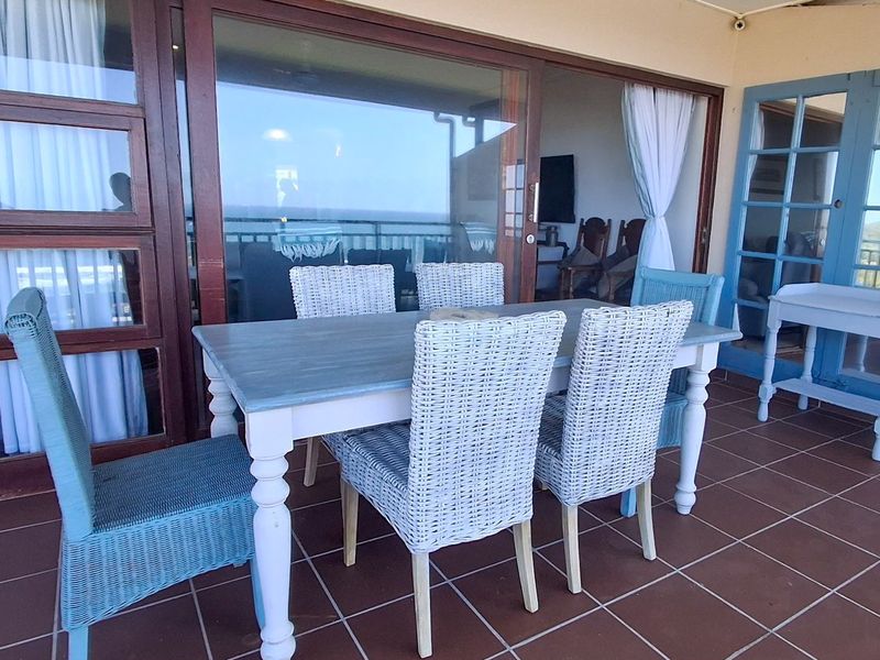 A covered balcony featuring tiled flooring and large sliding glass doors, providing a seamless transition between indoor and outdoor living spaces.