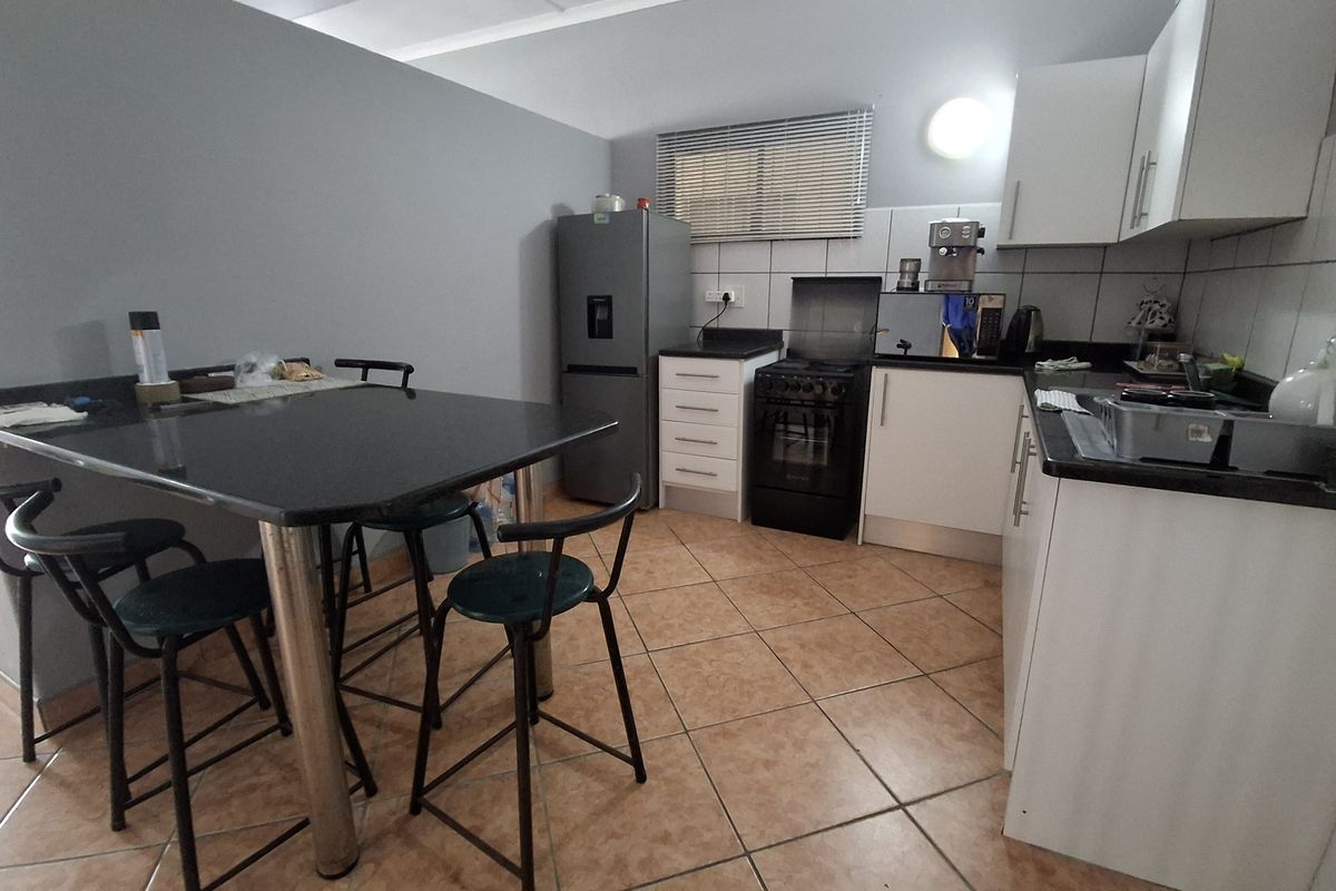 A functional kitchen featuring white cabinetry, dark granite countertops, tiled flooring, and a freestanding stove, providing a practical workspace for daily cooking.