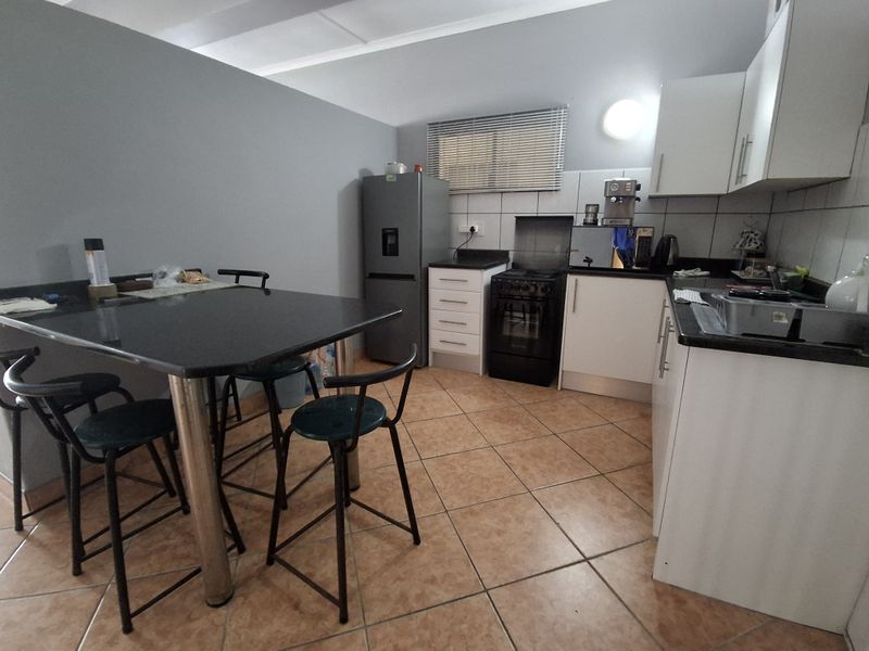 A functional kitchen featuring white cabinetry, dark granite countertops, tiled flooring, and a freestanding stove, providing a practical workspace for daily cooking.