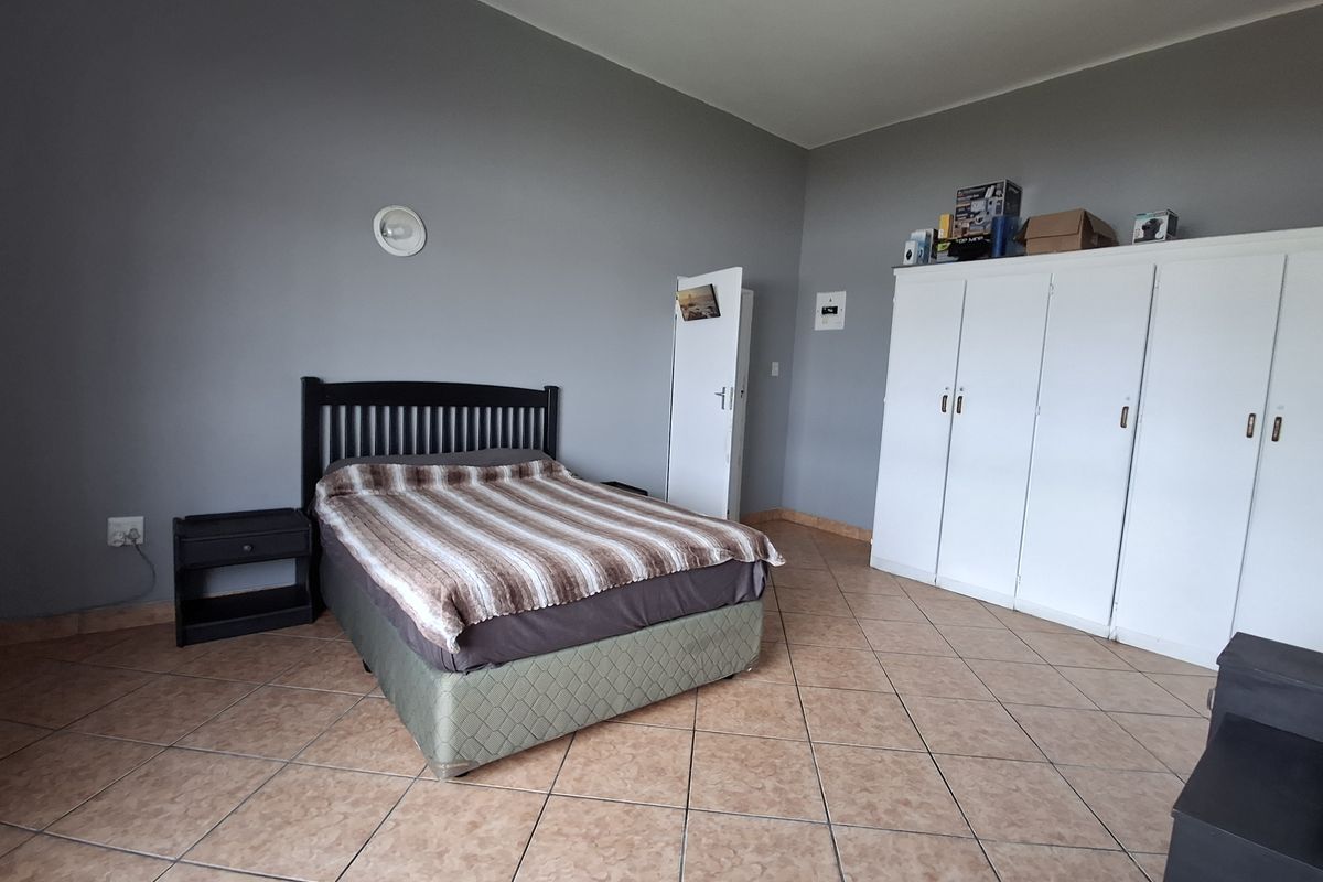 Spacious bedroom featuring tiled flooring and a large built-in wardrobe, offering a neutral base for personalization.
