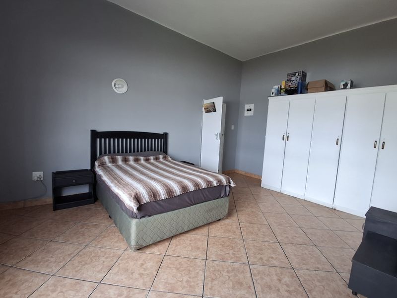 Spacious bedroom featuring tiled flooring and a large built-in wardrobe, offering a neutral base for personalization.