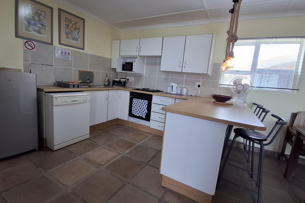 A functional kitchen featuring white cabinetry, laminate countertops, a tiled backsplash, and a breakfast bar, providing a practical layout for daily use.