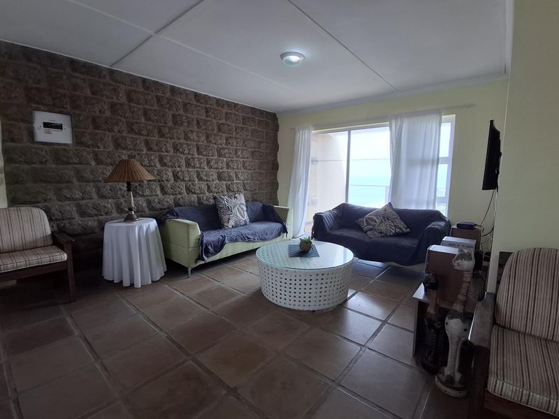 A living room featuring a prominent stone accent wall, tiled flooring, and large sliding glass doors providing natural light and access to the exterior.