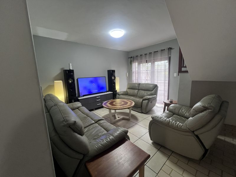 A comfortable living room featuring tiled flooring and a sliding glass door providing access to the exterior.