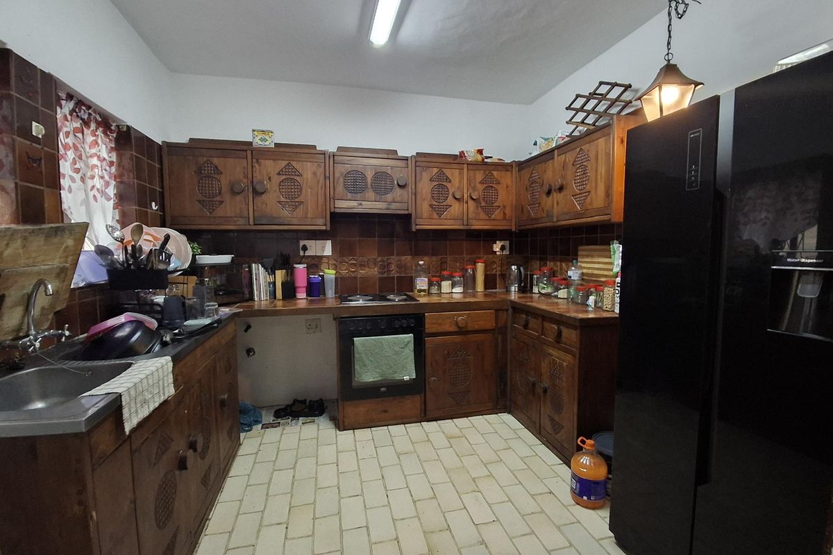 A dated kitchen featuring traditional wooden cabinetry, tiled backsplash, and built-in cooking appliances, offering significant potential for a modern renovation.