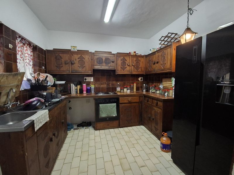 A dated kitchen featuring traditional wooden cabinetry, tiled backsplash, and built-in cooking appliances, offering significant potential for a modern renovation.