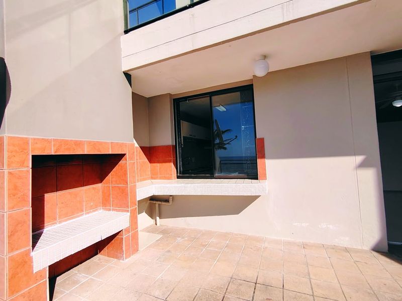 Covered balcony featuring a built-in braai area with tiled surfaces, providing a functional outdoor space for entertaining.