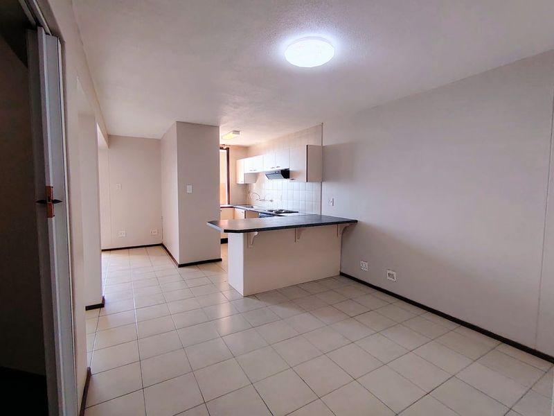 Open plan living and kitchen area featuring tiled flooring, a breakfast bar, and functional kitchen cabinetry with a built-in extractor fan.