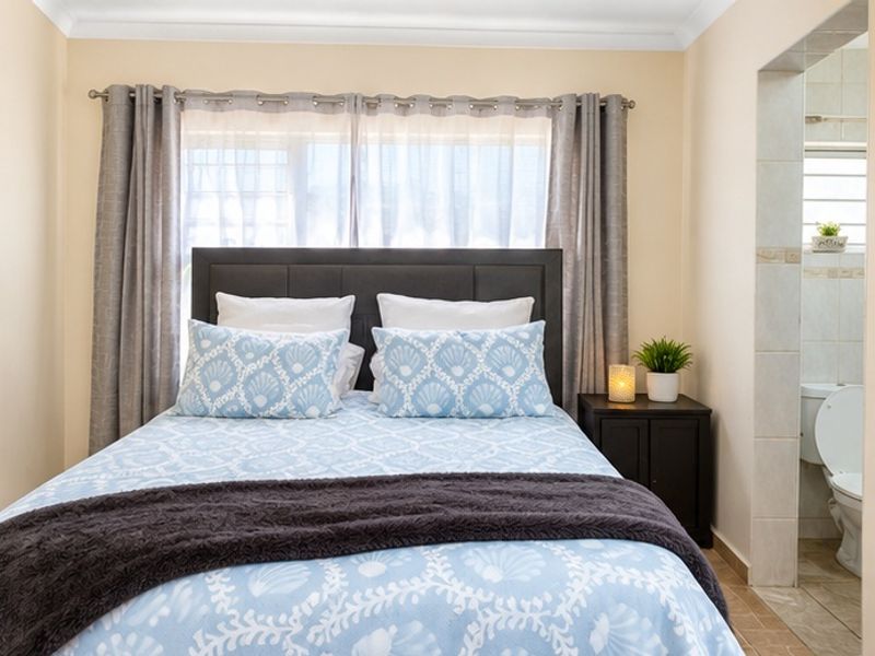 A well-maintained bedroom featuring neutral wall tones, cove cornicing, and an adjoining en-suite bathroom with tiled flooring.