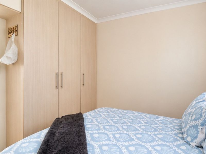 A well-maintained bedroom featuring light wood-finish built-in wardrobes and neutral wall tones.