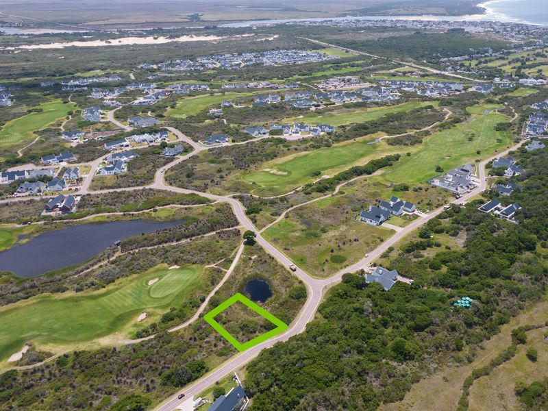 Aerial view of a vacant residential plot situated within a coastal golf estate, offering scenic surroundings and proximity to local amenities.