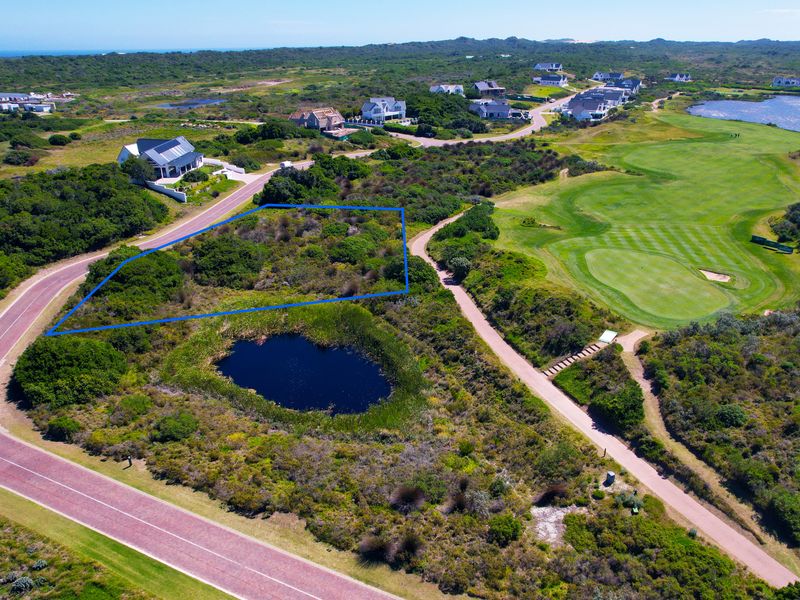 Aerial view of a vacant residential plot situated in a scenic estate, adjacent to a golf course and natural landscape.