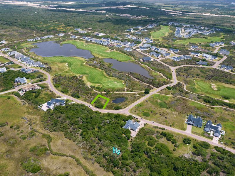 Aerial view of a vacant residential plot situated within a scenic golf estate, surrounded by natural landscape and established residential properties.