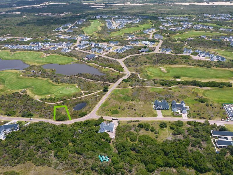 Aerial view of a vacant residential plot situated within a scenic golf estate, surrounded by natural coastal vegetation and established residential properties.