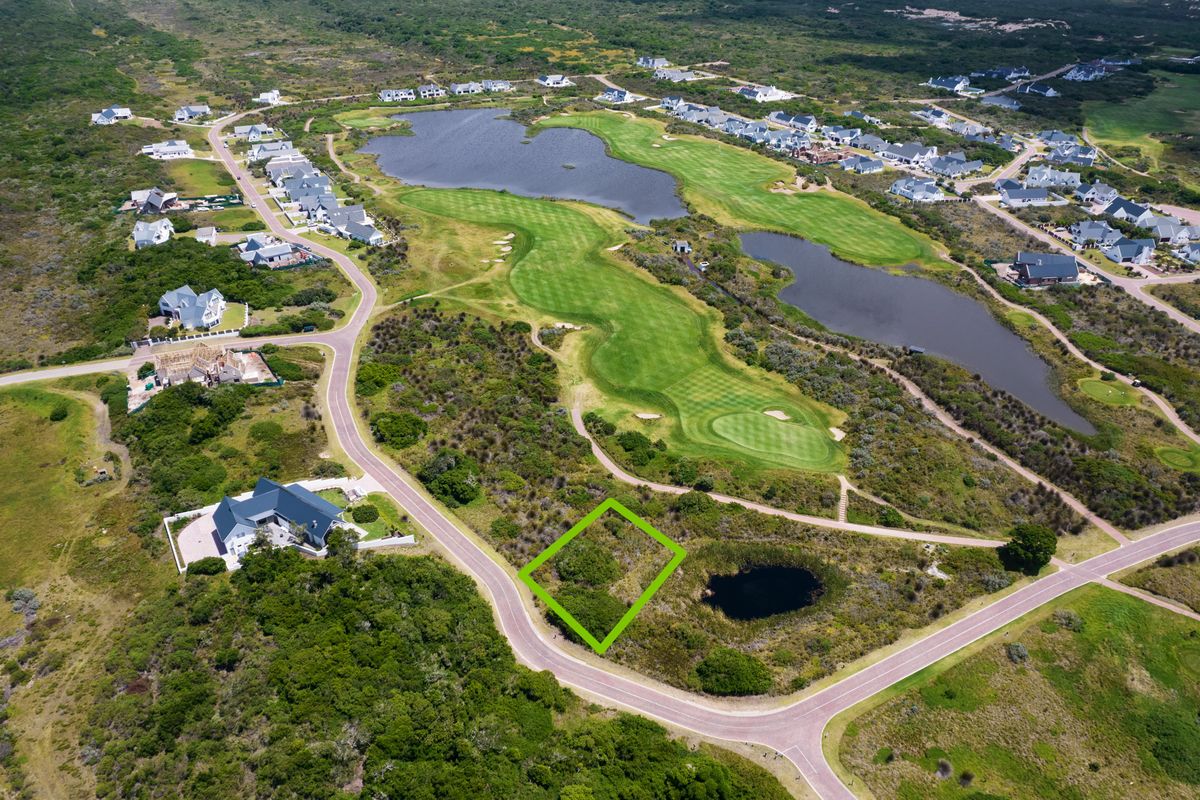 Aerial view of a vacant residential plot situated within a golf estate, featuring paved road access and proximity to natural landscape and water features.