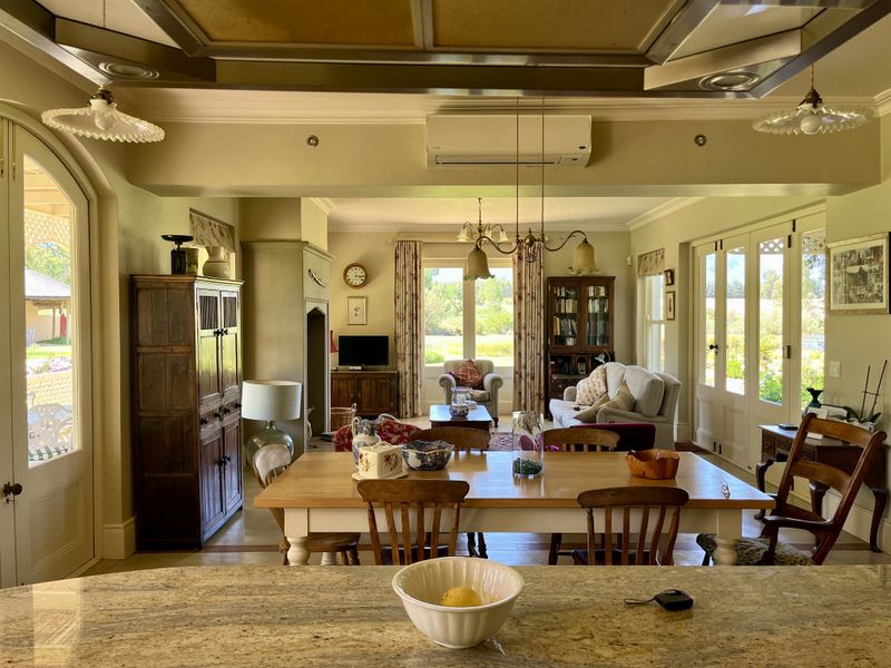 Spacious open-plan living and dining area featuring a granite kitchen island, split-system air conditioning, and abundant natural light through multiple sets of french doors.