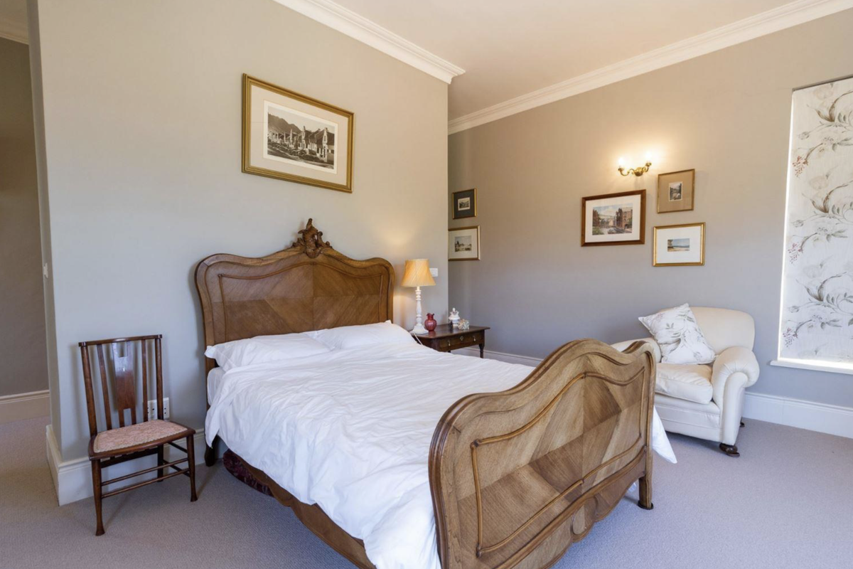 A spacious and well-maintained bedroom featuring neutral wall tones, crown molding, and soft carpet flooring, creating a comfortable and inviting atmosphere.