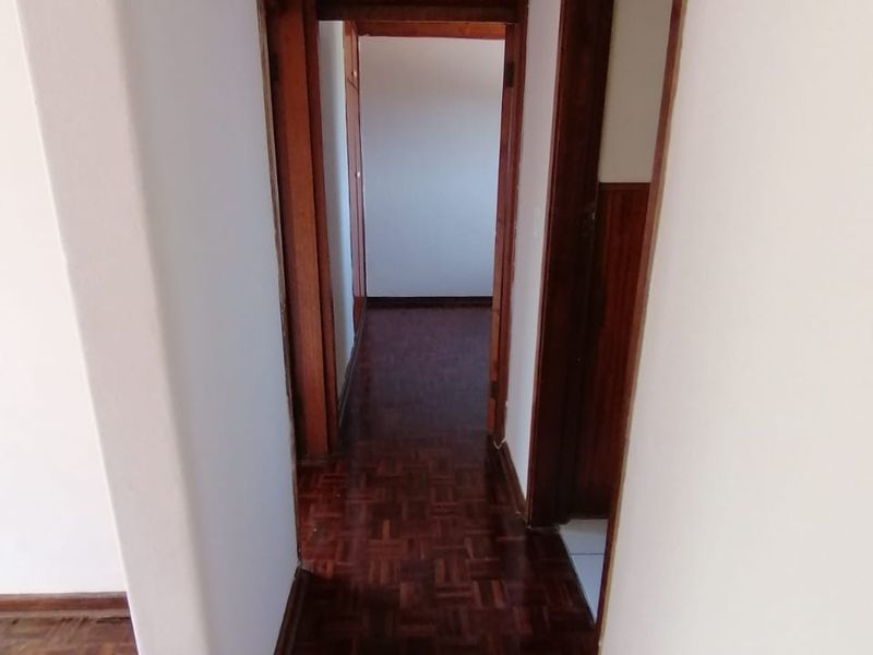 A functional hallway featuring traditional parquet flooring and wooden door frames, connecting various rooms within the apartment.