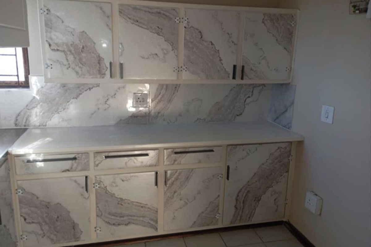 A compact kitchen area featuring built-in cabinetry with a marble-effect finish, tiled backsplash, and tiled flooring, offering a functional space for culinary activities.