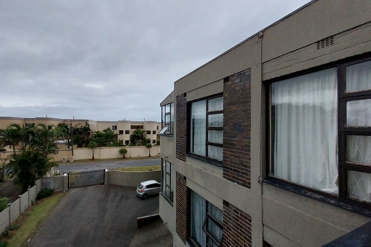 Exterior view of the apartment building showing the rear facade, brick detailing, steel windows, and the shared driveway area.