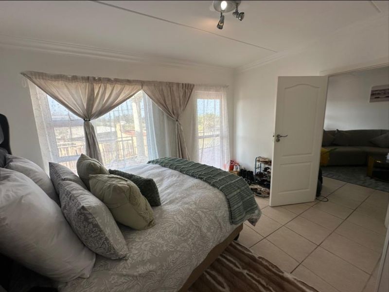 A bedroom featuring tiled flooring, a coved ceiling, and a sliding glass door providing access to an outdoor balcony area.