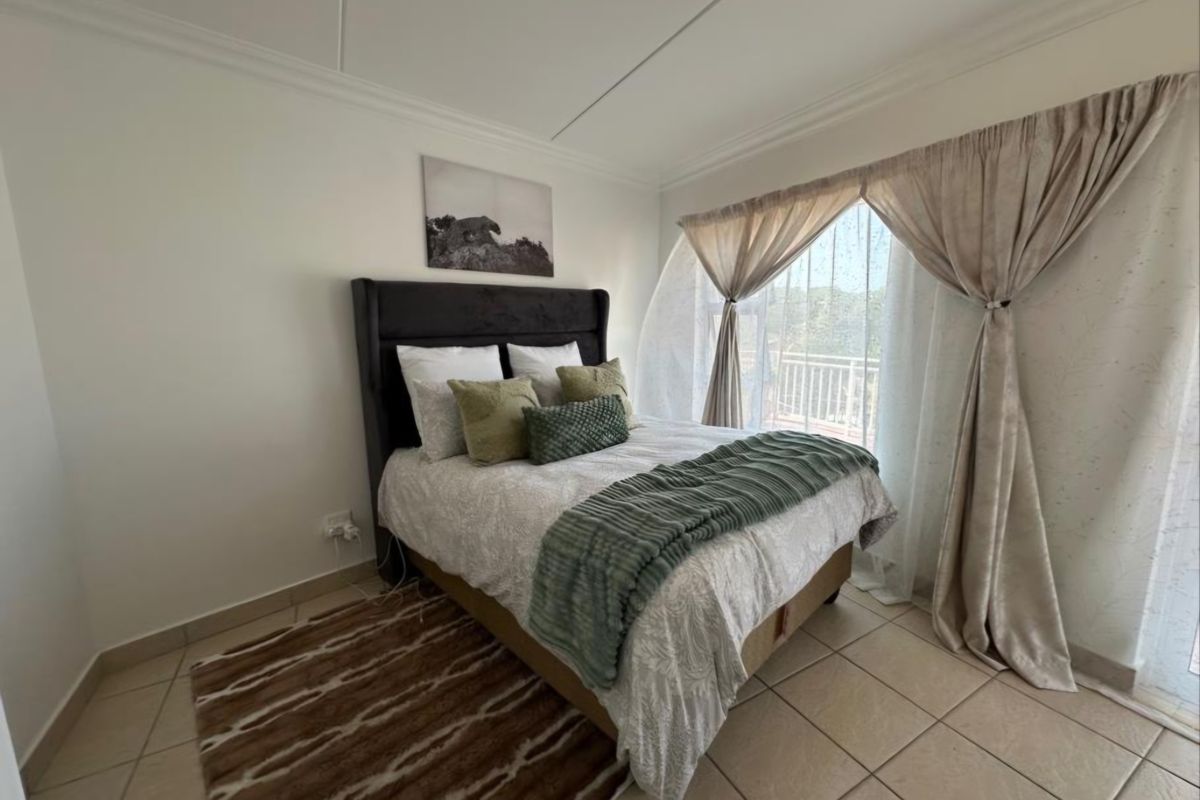 A well-lit bedroom featuring tiled flooring, coved ceilings, and a sliding glass door providing access to an outdoor area.