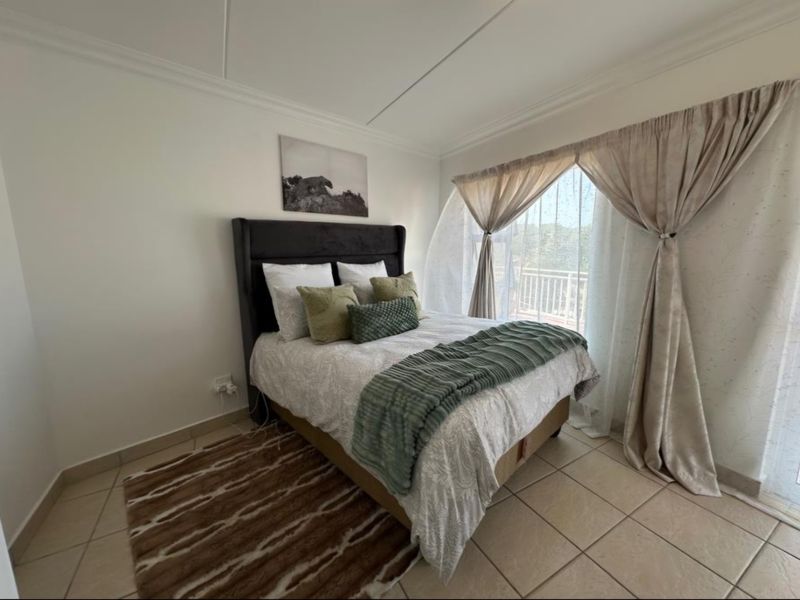 A well-lit bedroom featuring tiled flooring, coved ceilings, and a sliding glass door providing access to an outdoor area.