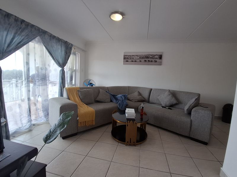 A comfortable living room featuring tiled flooring and a large sliding glass door that provides access to the outdoor area.