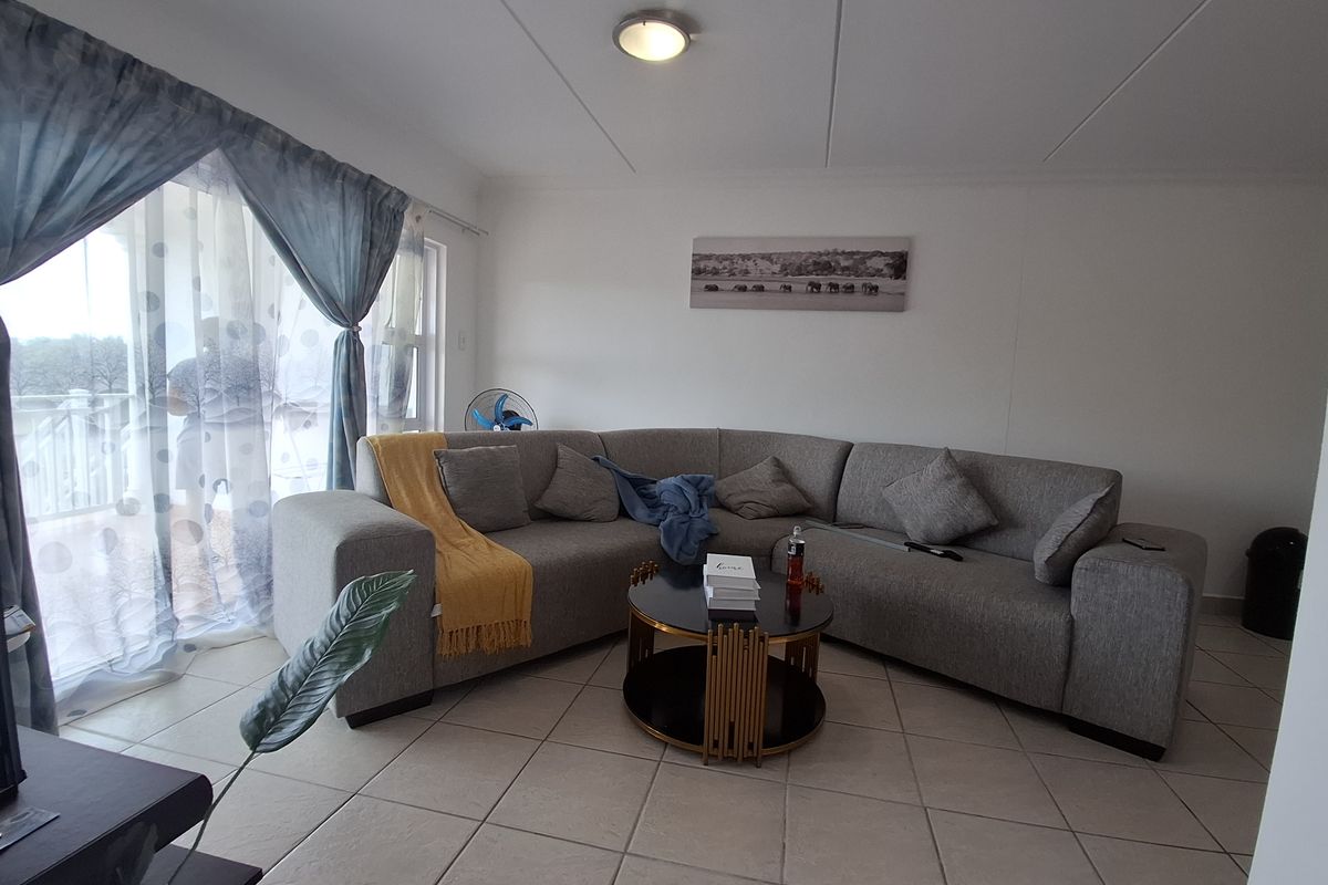 A comfortable living room featuring tiled flooring and a large sliding glass door that provides access to the outdoor area.
