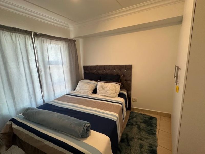 A compact bedroom featuring tiled flooring, built-in wardrobe storage, and decorative ceiling cornicing.