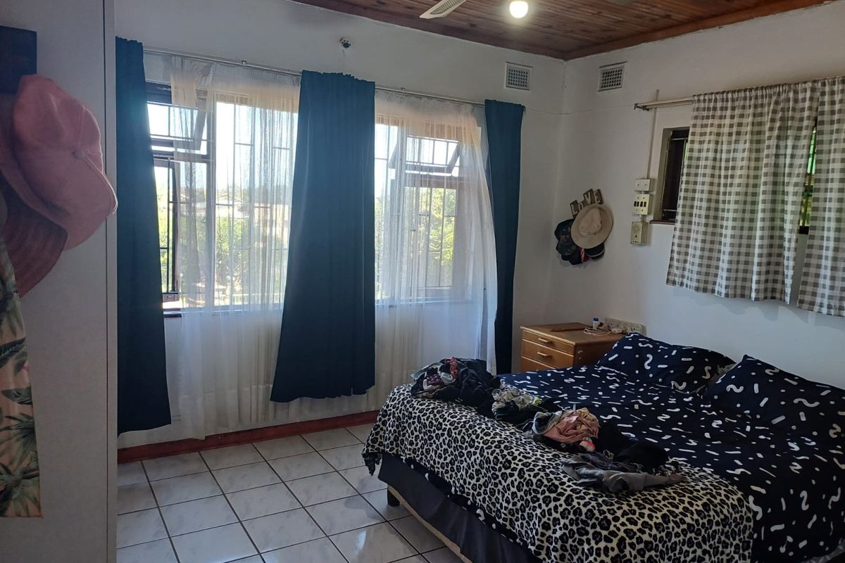 A bedroom featuring tiled flooring, a timber ceiling with a ceiling fan, and large windows fitted with security burglar bars.