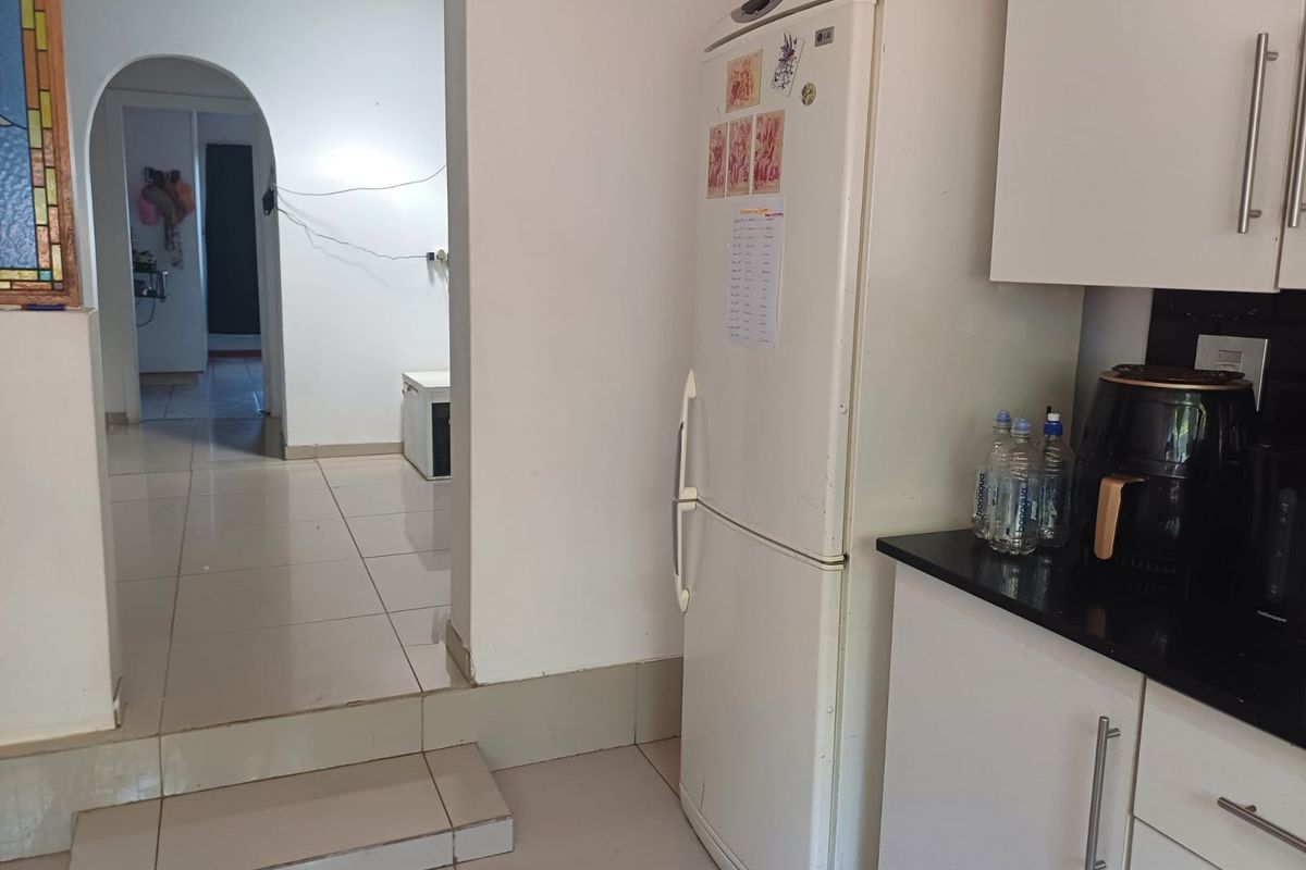 Kitchen area featuring built-in cabinetry, granite countertops, and tiled flooring, leading through an arched doorway to an adjacent living space.