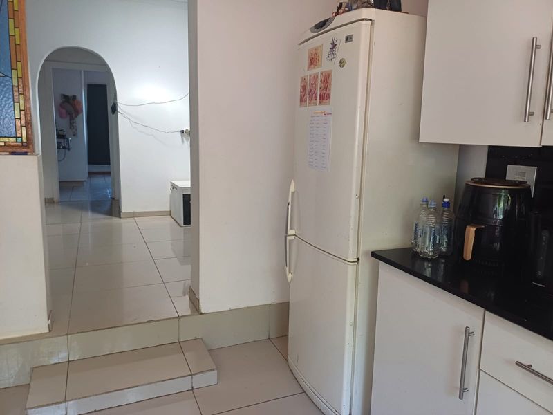 Kitchen area featuring built-in cabinetry, granite countertops, and tiled flooring, leading through an arched doorway to an adjacent living space.