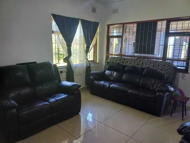 A living room featuring tiled flooring, large windows with security bars, and integrated air vents.