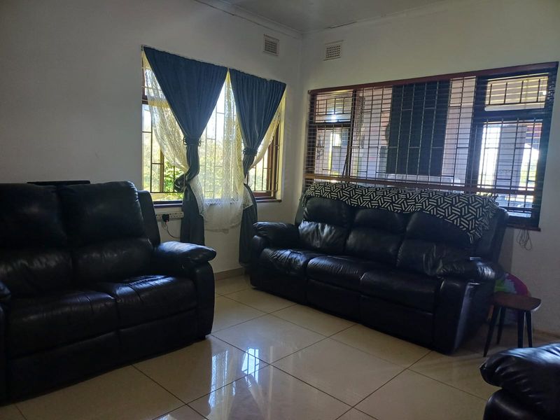 A living room featuring tiled flooring, security bars on windows, and fitted window treatments, providing a functional and secure living space.