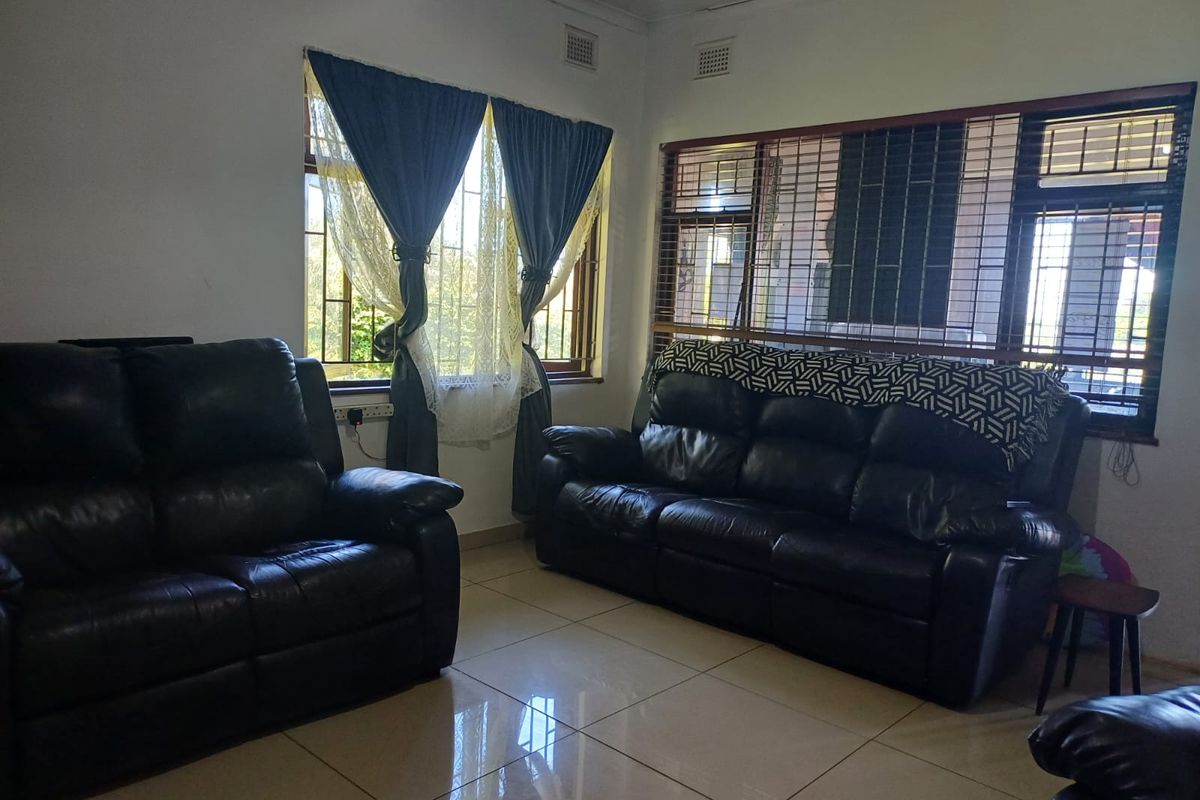A living room featuring tiled flooring, security bars on windows, and fitted window treatments, providing a functional and secure living space.