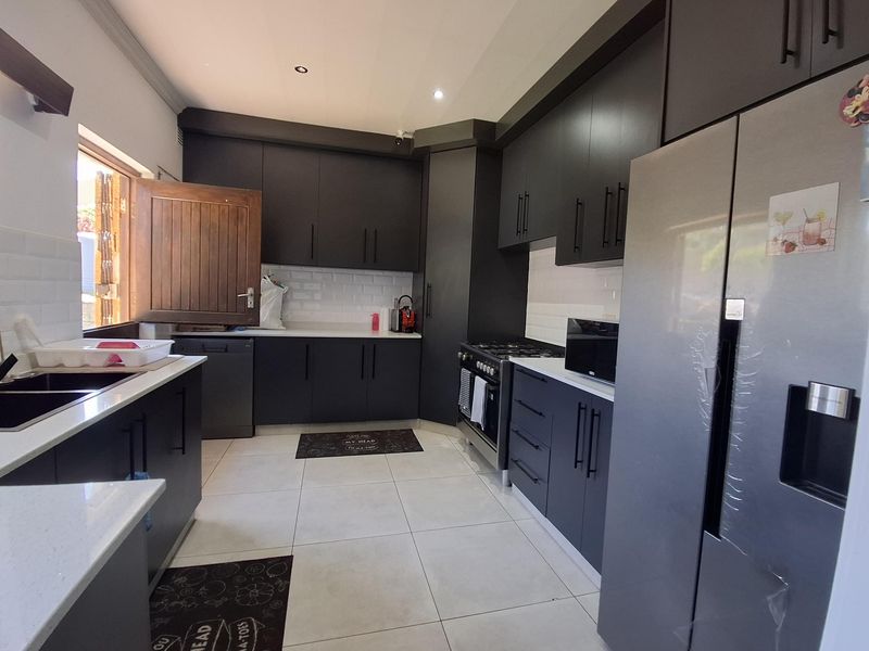 Modern kitchen featuring dark cabinetry, stone countertops, subway tile backsplash, and integrated gas stove with ample storage space.