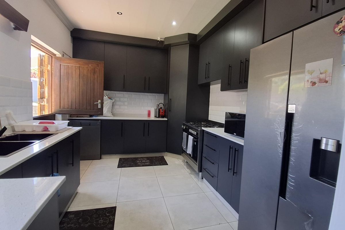 Modern kitchen featuring dark cabinetry, stone countertops, subway tile backsplash, and integrated gas stove with ample storage space.