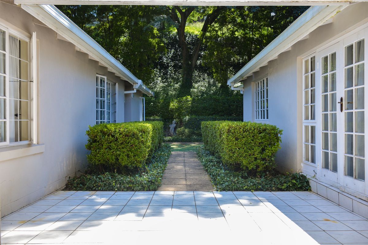 A well-maintained rear patio area featuring tiled flooring, a central paved walkway, and access to the home via classic french doors.