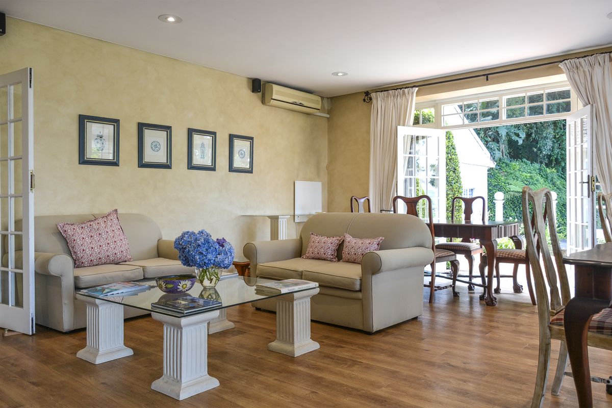 A bright living room featuring timber flooring, recessed lighting, and French doors opening to an outdoor area.