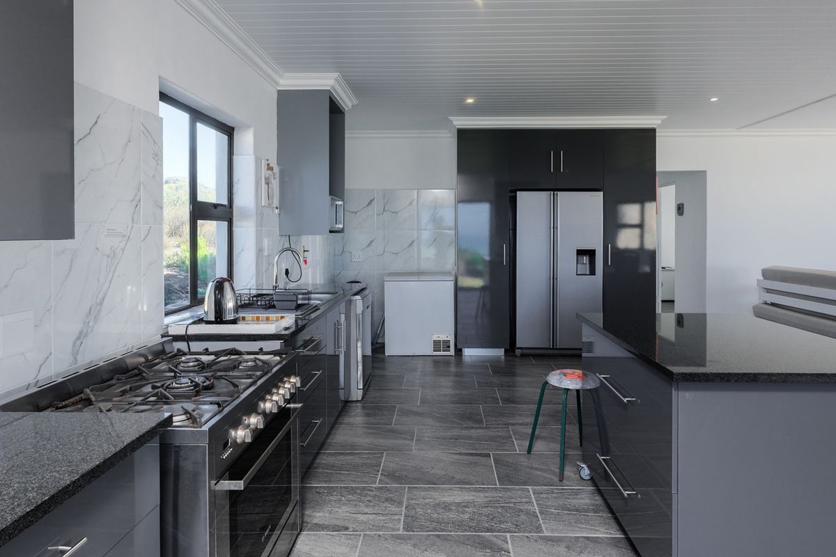 Modern kitchen featuring dark cabinetry, granite countertops, marble-look splashbacks, gas stove, and tiled flooring with a clean, contemporary aesthetic.