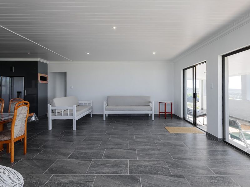 Spacious open-plan living and dining area featuring large format floor tiles, recessed lighting, and sliding glass doors leading to an outdoor patio.