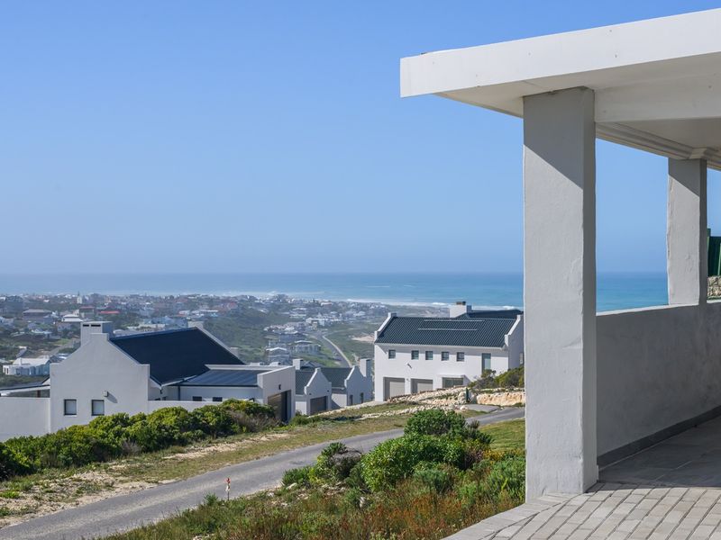 A spacious covered patio offering expansive coastal and neighbourhood views, featuring solid concrete pillars and durable tiled flooring.
