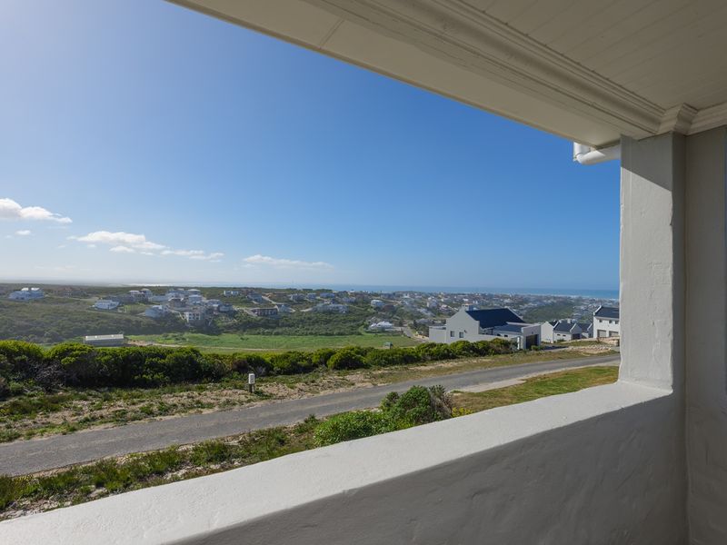 A covered balcony offering expansive elevated views over the surrounding coastal landscape and residential neighborhood.