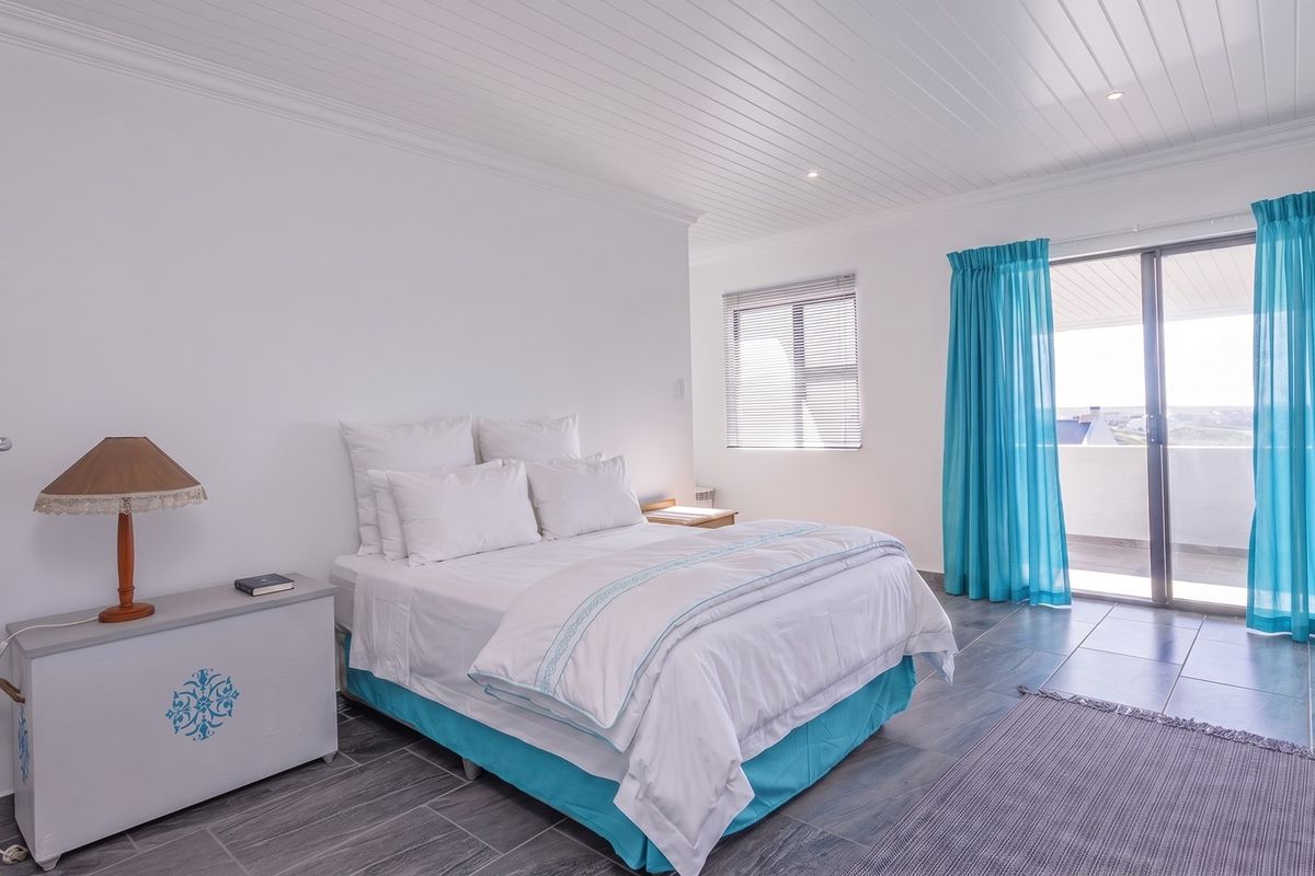 A bright bedroom featuring tiled flooring, a tongue and groove ceiling, and a sliding glass door providing access to an outdoor balcony.