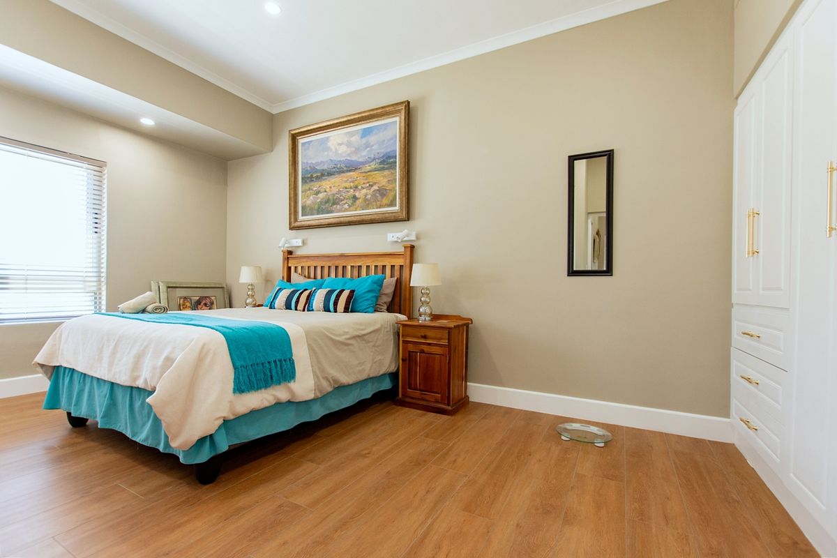 A well-maintained bedroom featuring wood-look laminate flooring, built-in cabinetry, and neutral wall tones, providing a clean and functional living space.